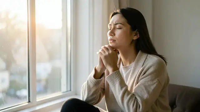 A person sitting quietly by a window practising slow breathing