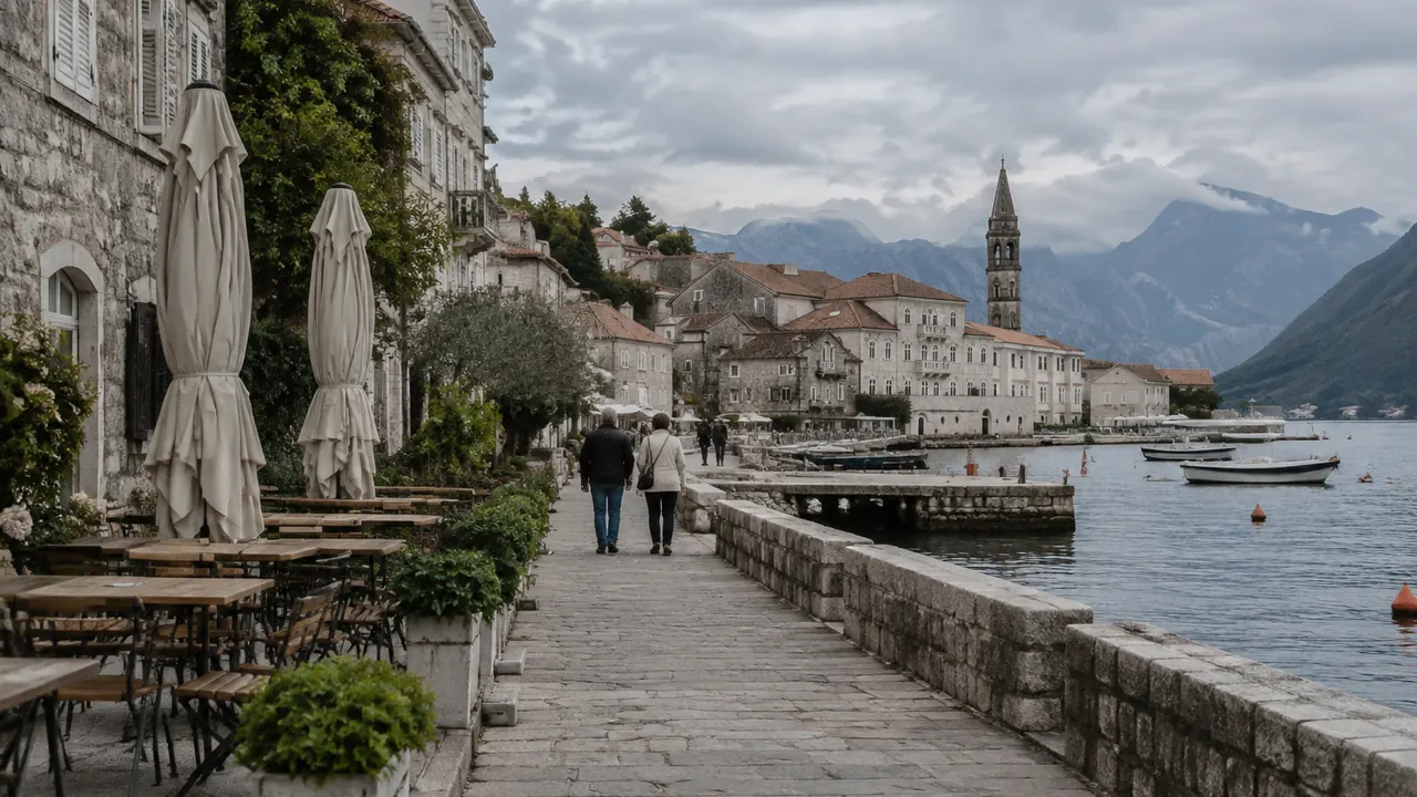 A quiet coastal town in early autumn with a few pedestrians, closed plain cafe umbrellas and overcast skies.